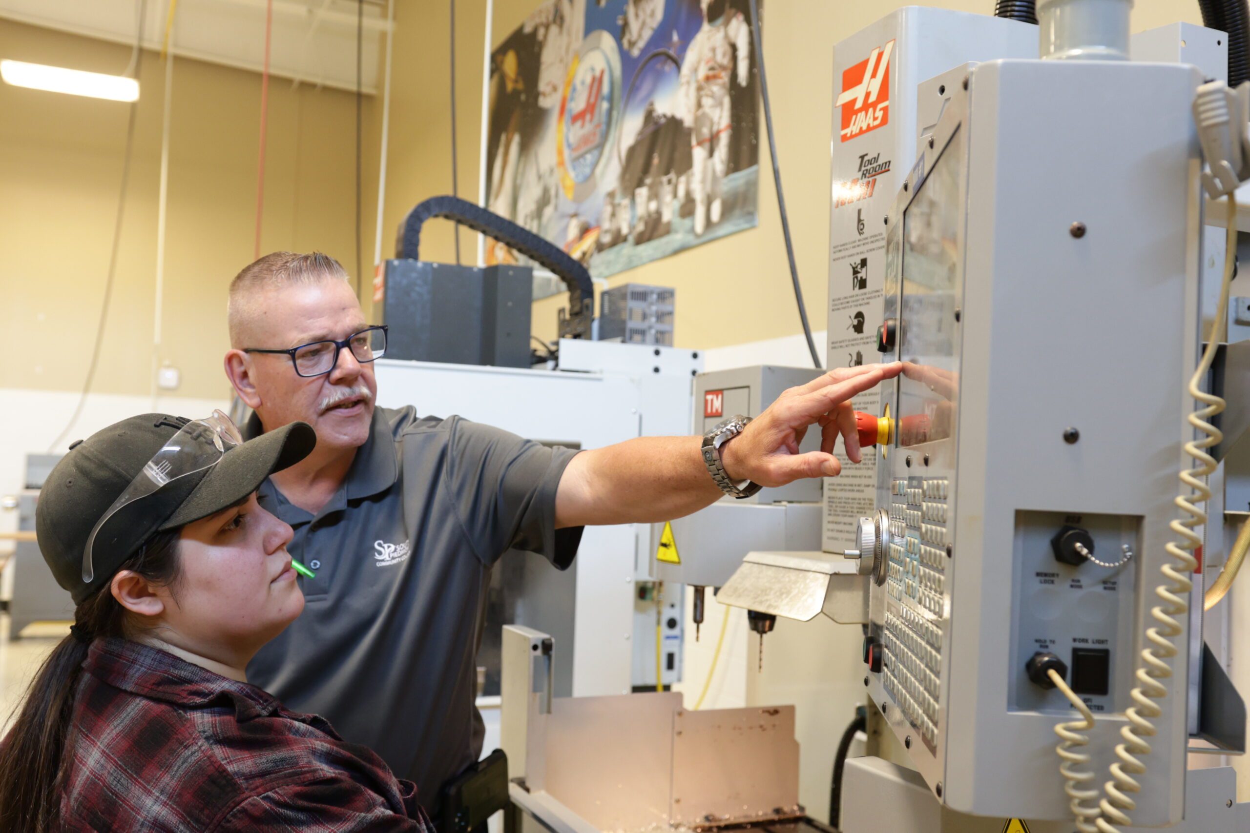 Male instructor helping a female student to use machining equipment at South Piedmont. 
