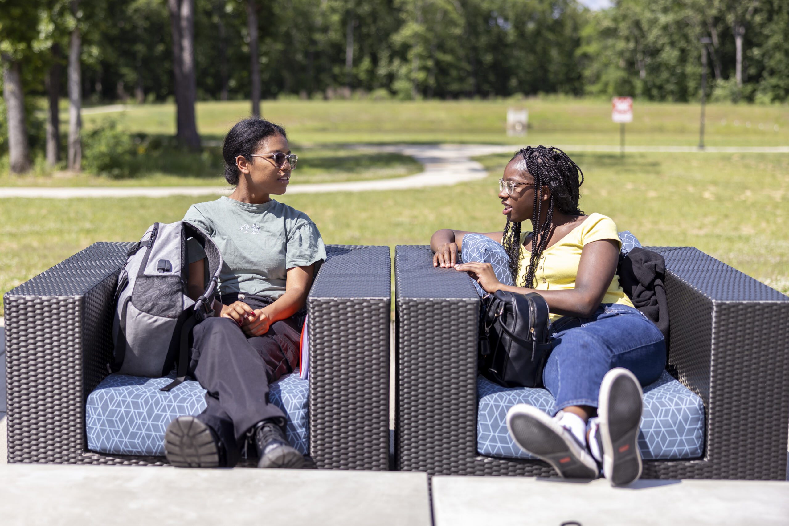 Two students sitting on the outdoor chairs.