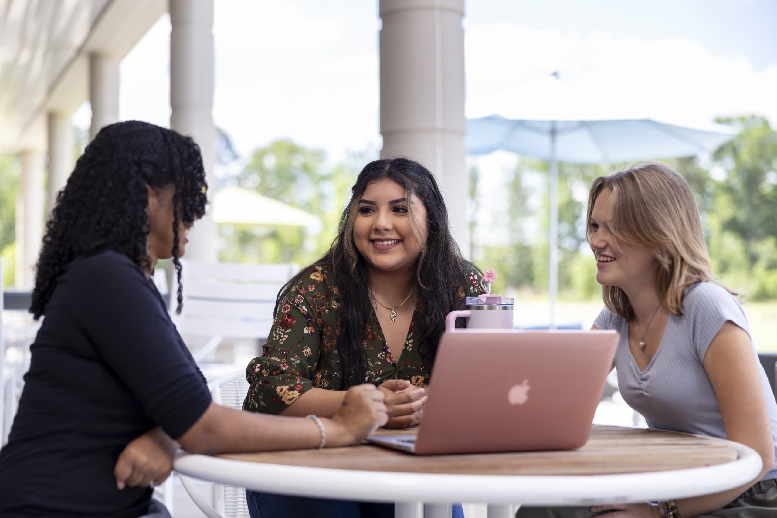 Three students sitting by outside area.