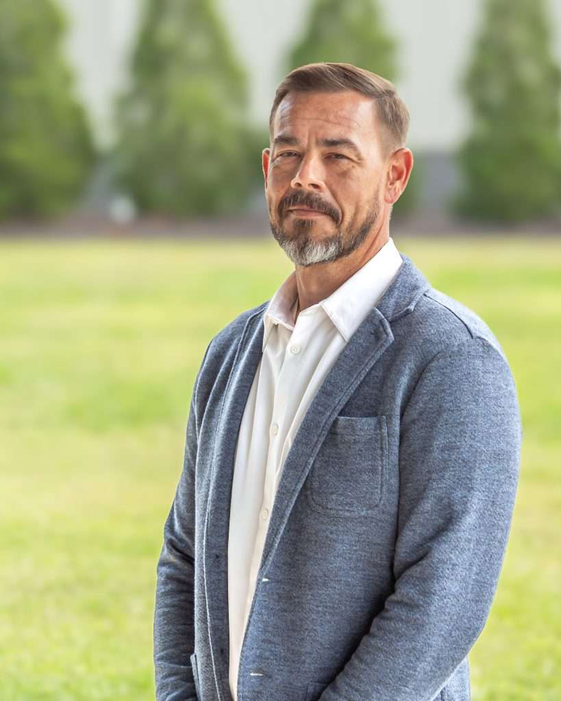 Photo of a man in a grey jacket.