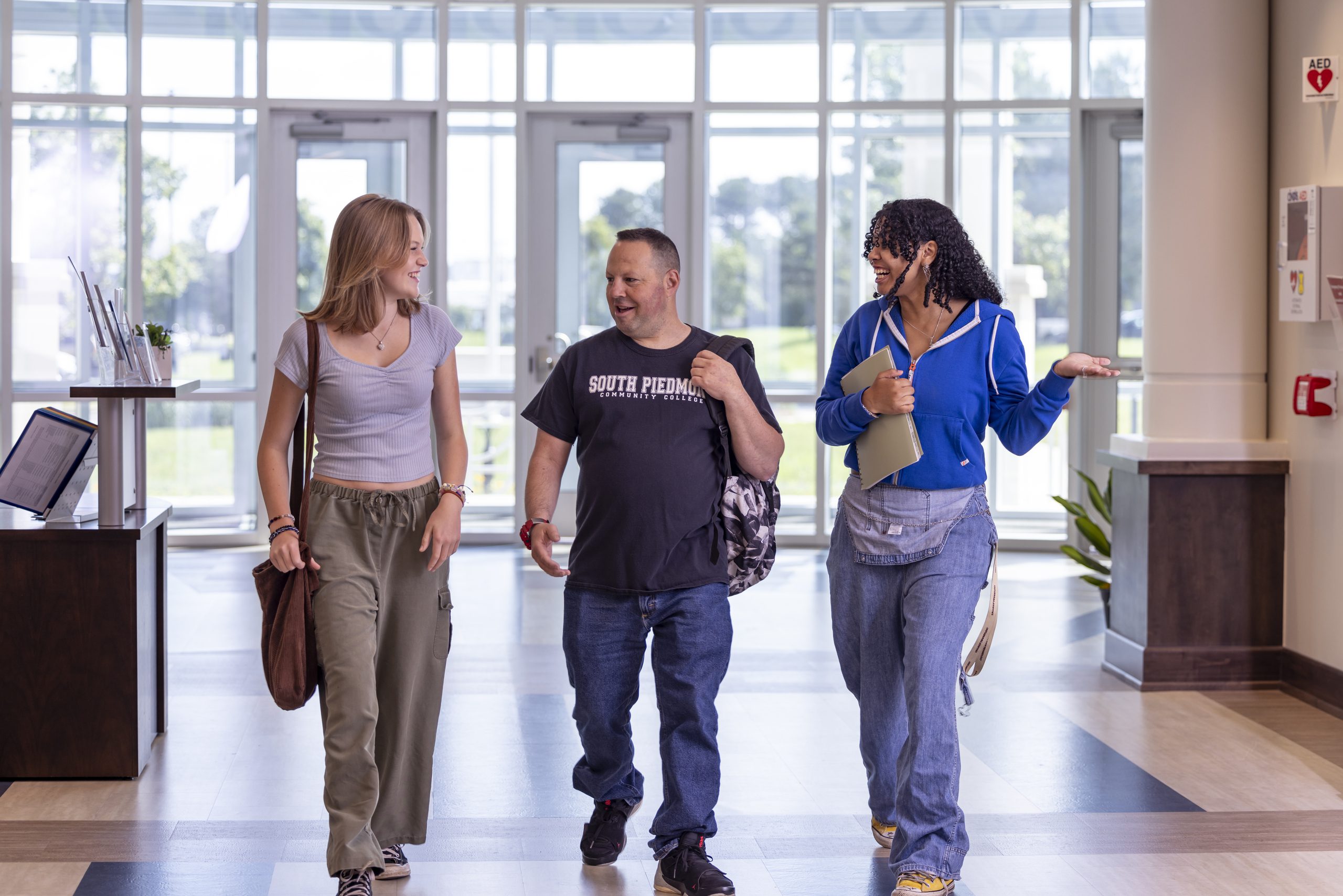 Three students walking into main OCH building hallway.