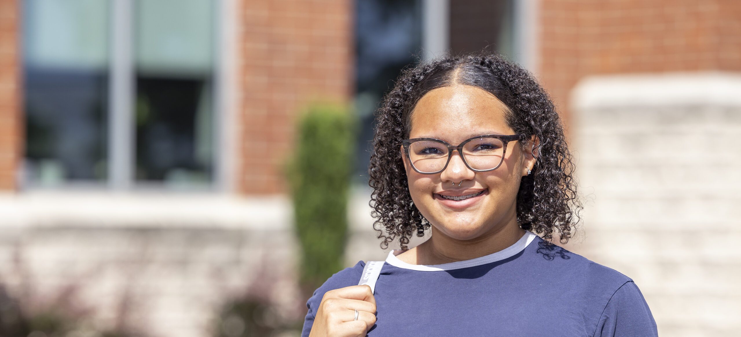 South Piedmont student standing in front of OCH building, wearing a backpack and glasses.