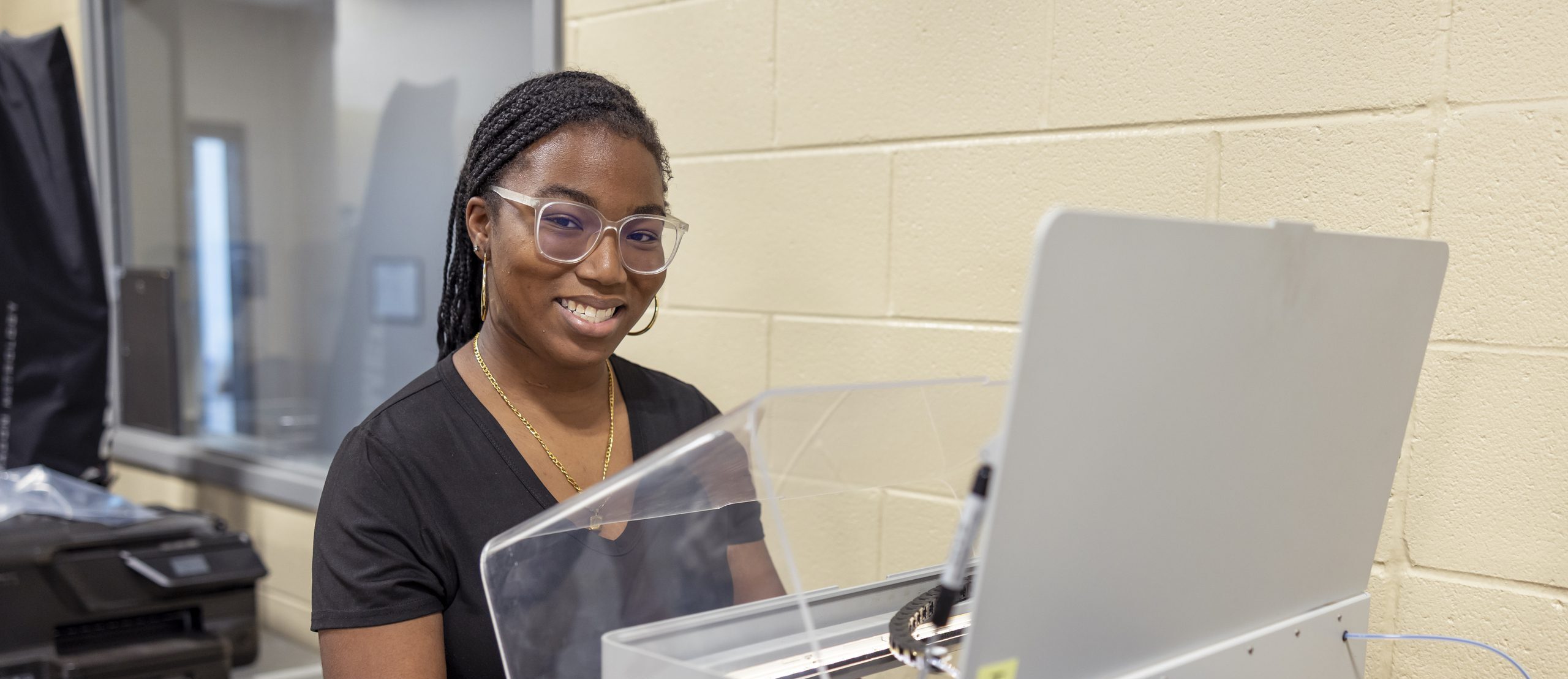 Student in front of a manufacturing machine.