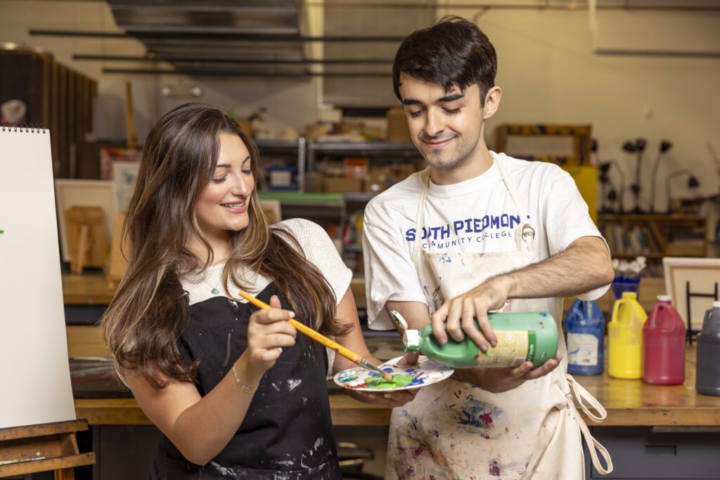 Two students working with paint in South Piedmont's Fine Arts studio.