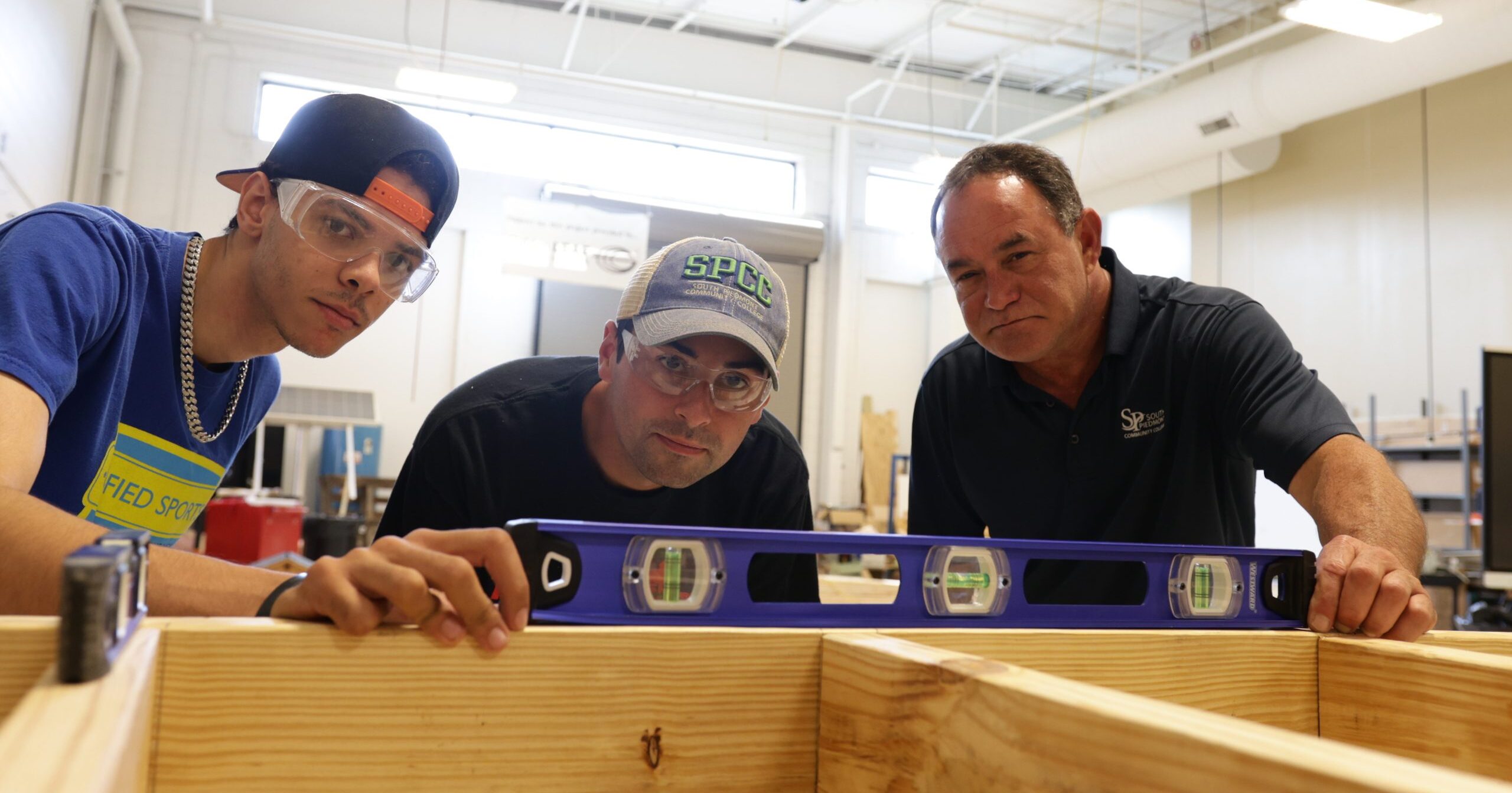 Two students and an instructor from the Construction Management program examining a level tool.