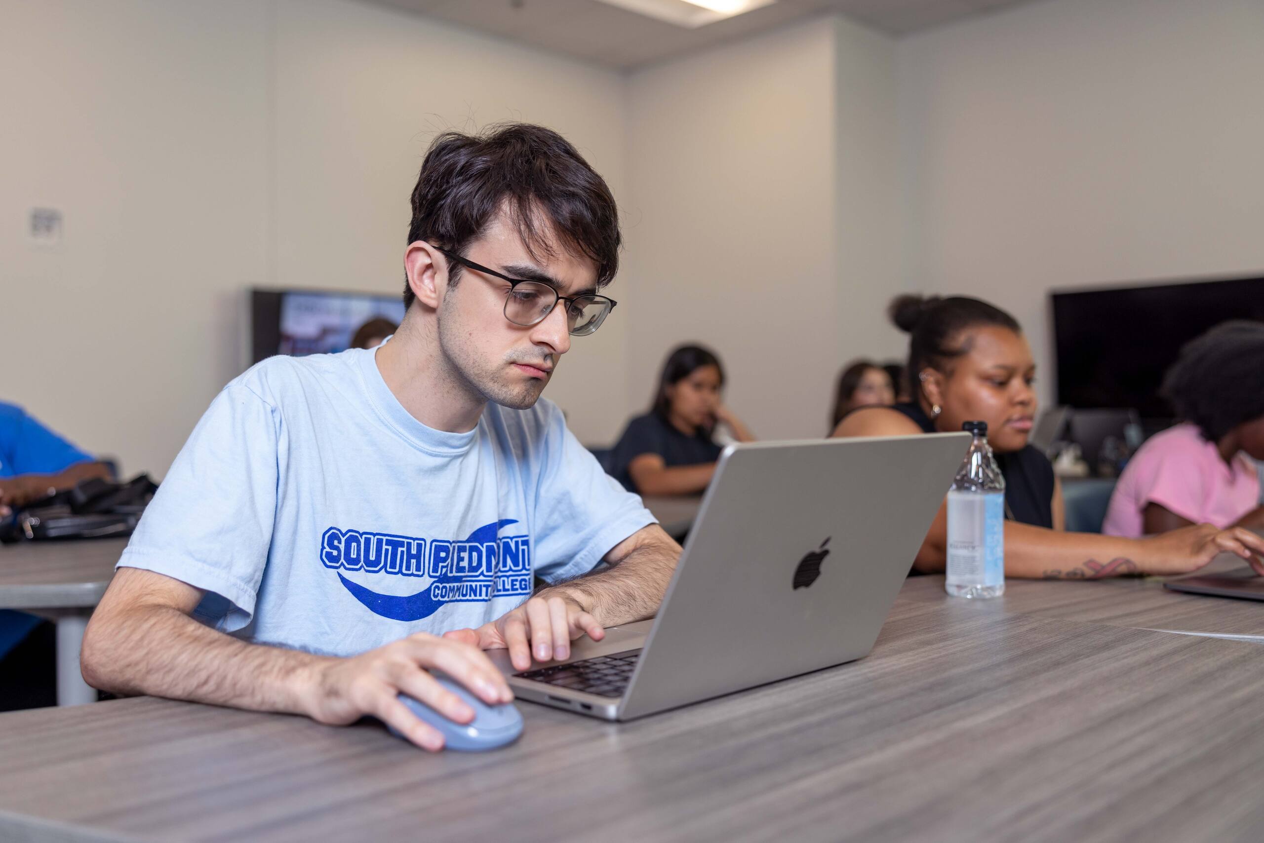 Student focused on his laptop inside a classroom.