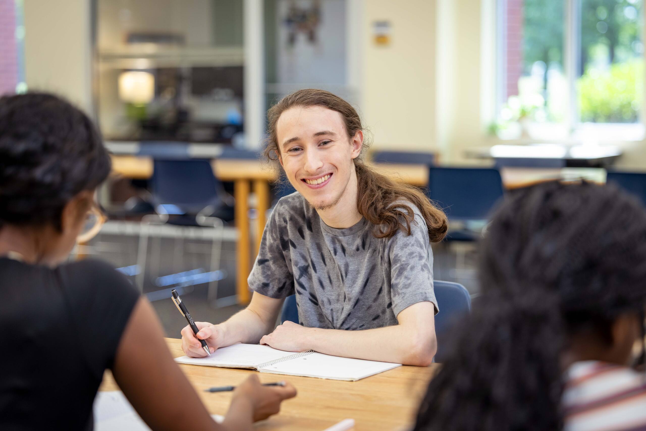 Student smiling at the camera, inside of the library.