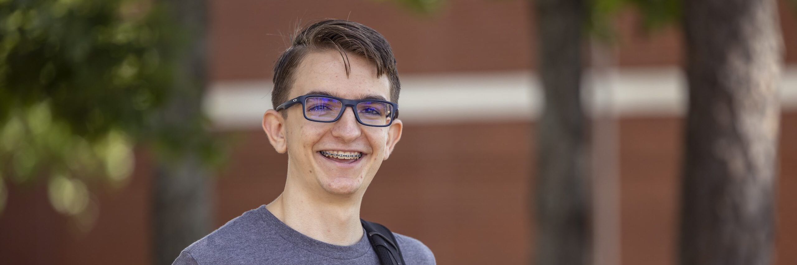 A male student wearing glasses and smiling at the camera.