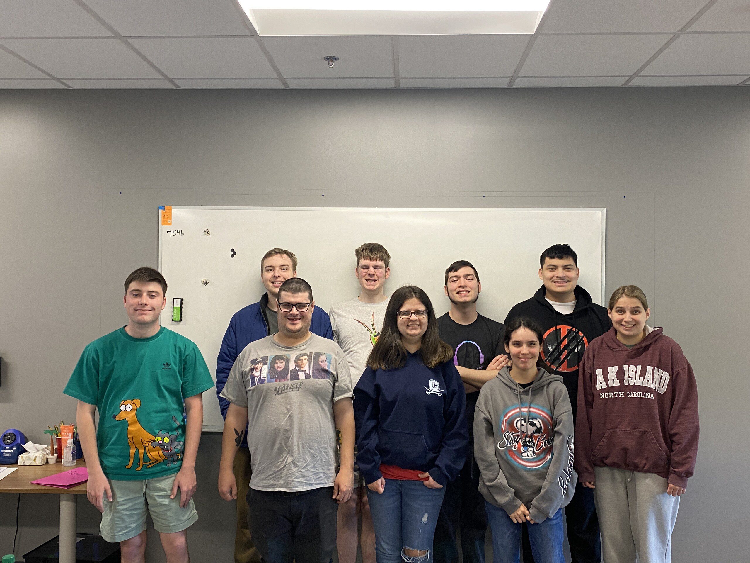 A group of students standing in a classroom, smiling at the camera.