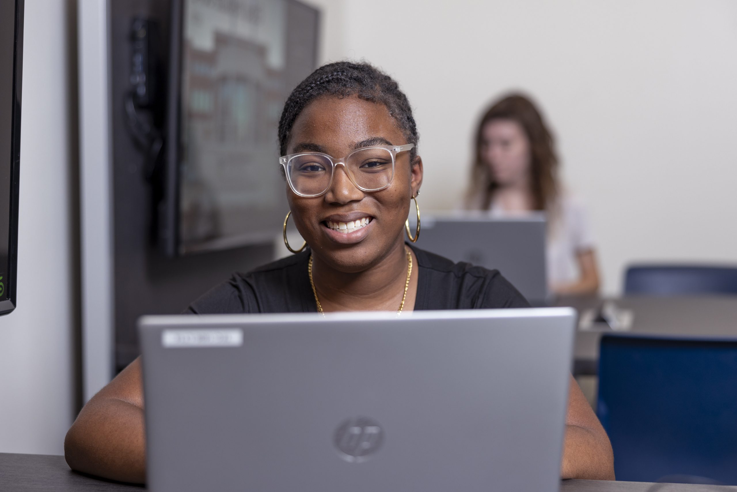 Student sitting inside a classroom with a laptop.