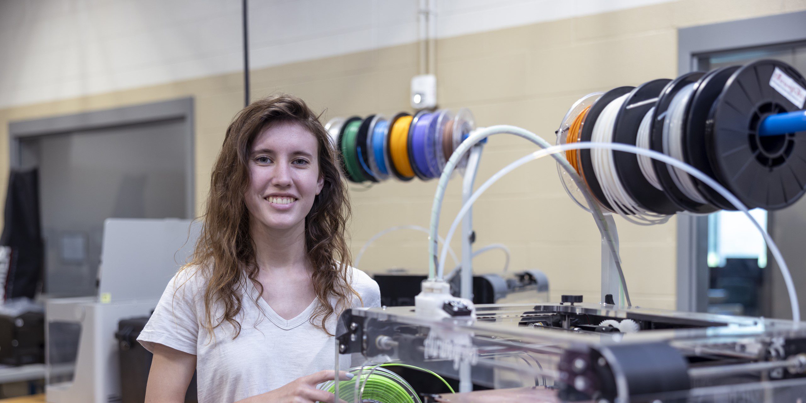 Student smiling in front of mechatronics equipment.