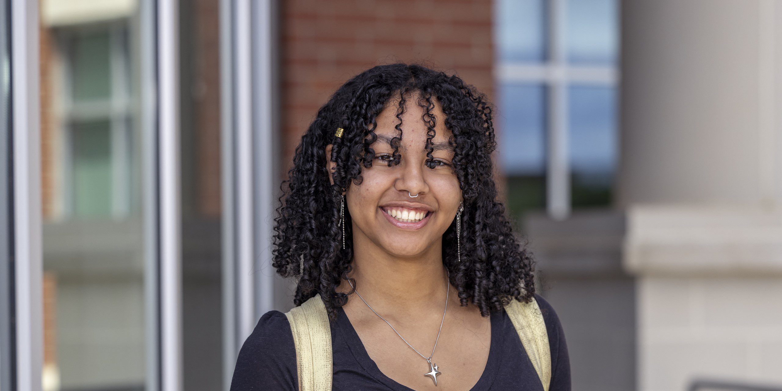 Female student with a backpack smiling in front of OCH main building.