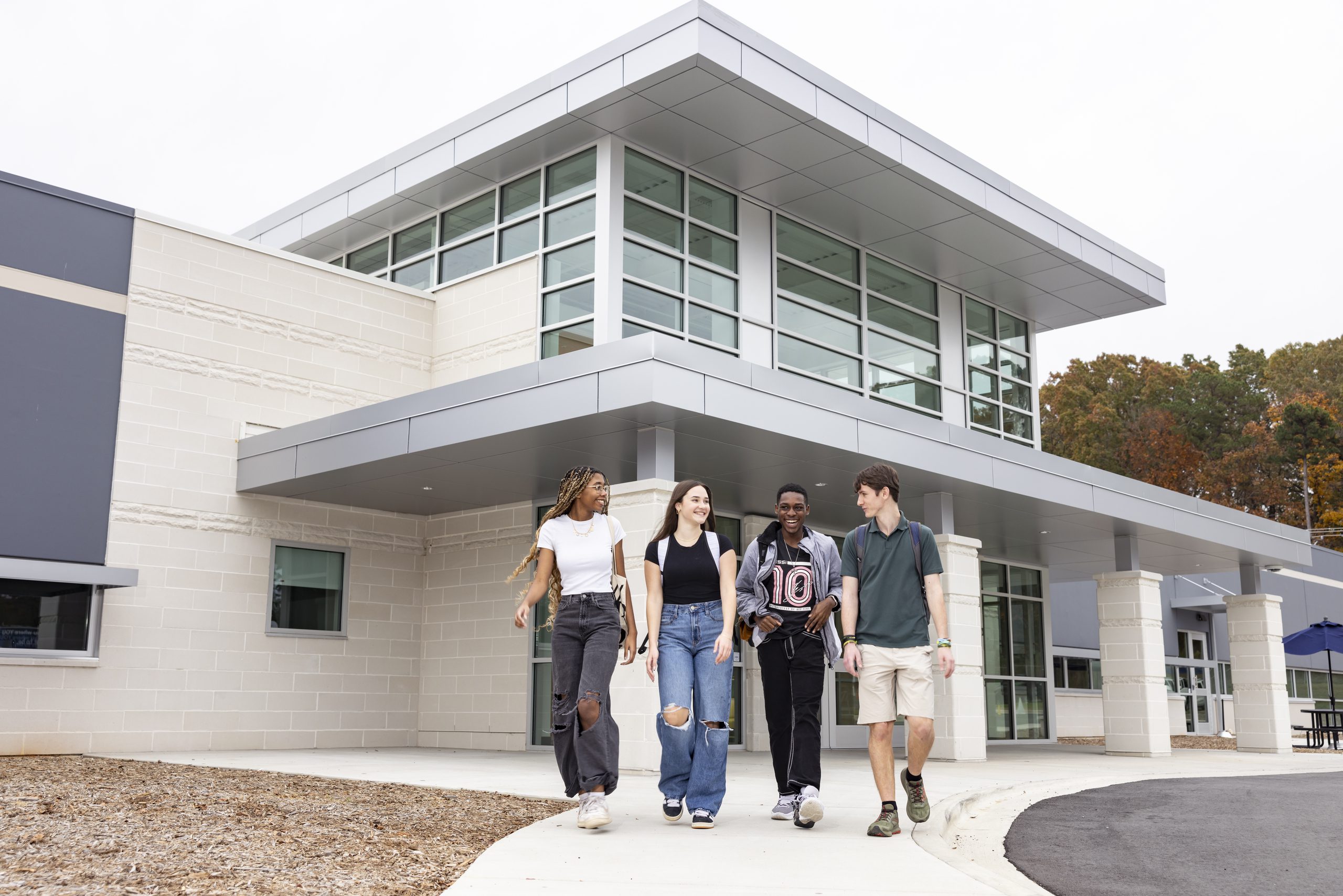 Four students walking in front of Building A on South Piedmont's Old Charlotte Highway campus.