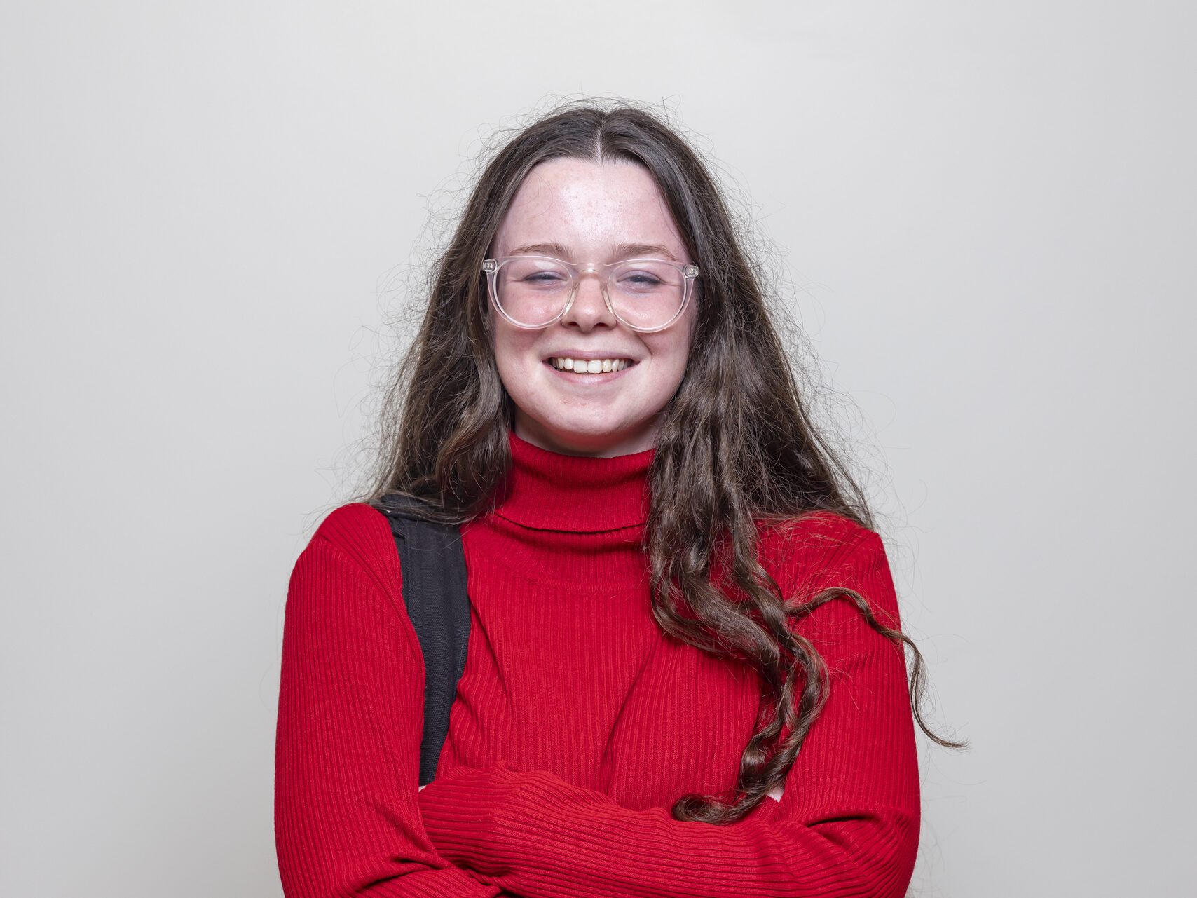 A full shot of a female student standing confidently in a hallway, looking at the camera.