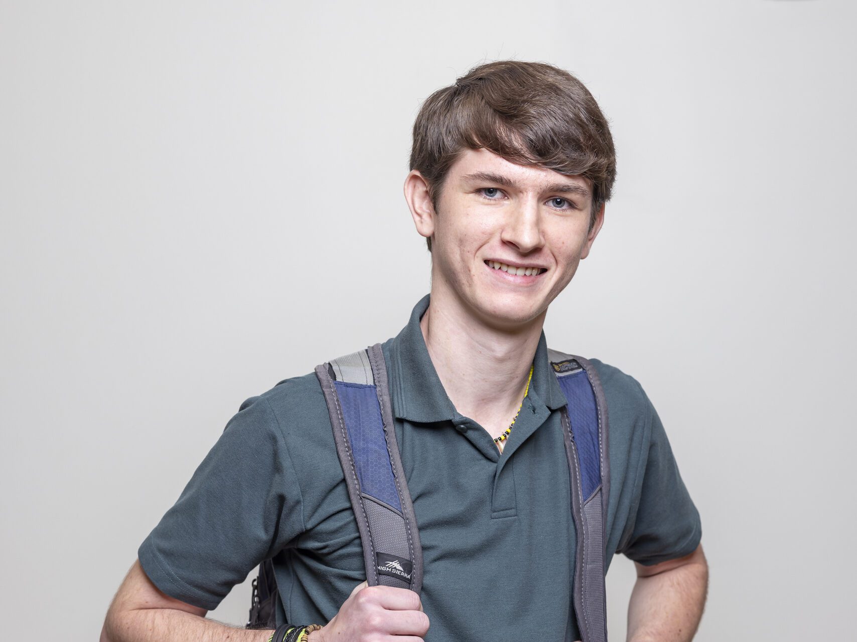 A full shot of a male student standing confidently in a hallway, looking at the camera.