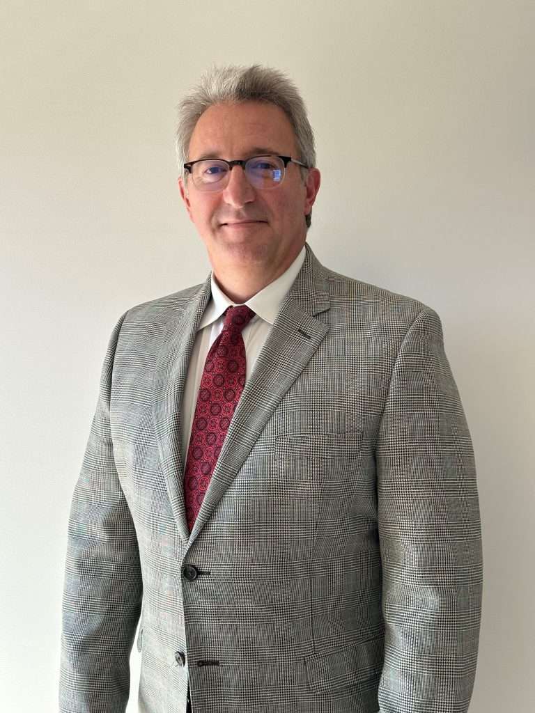 Photo of a man in a grey suit.
