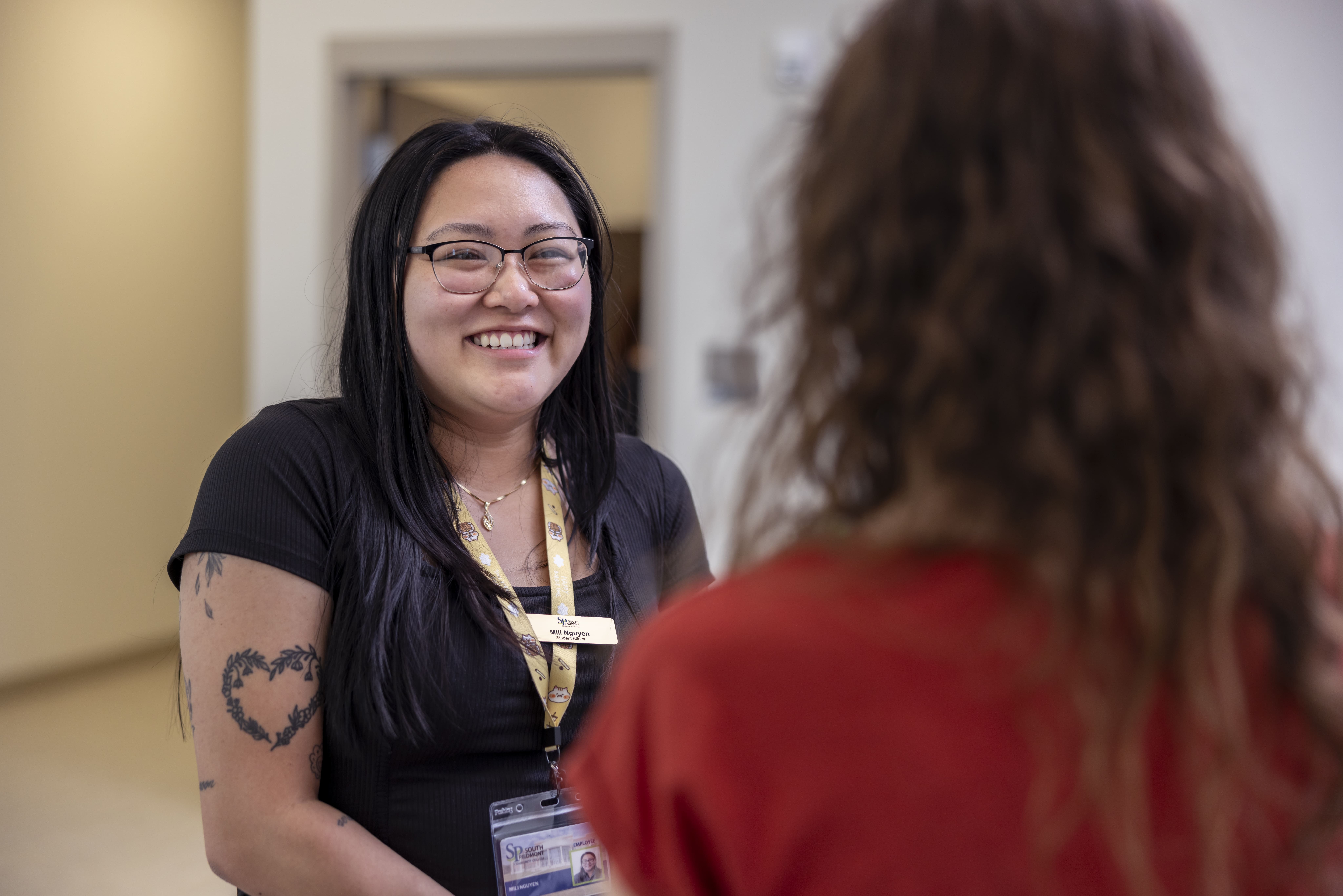 Photo of a female South Piedmont employee smiling while talking with a female student.