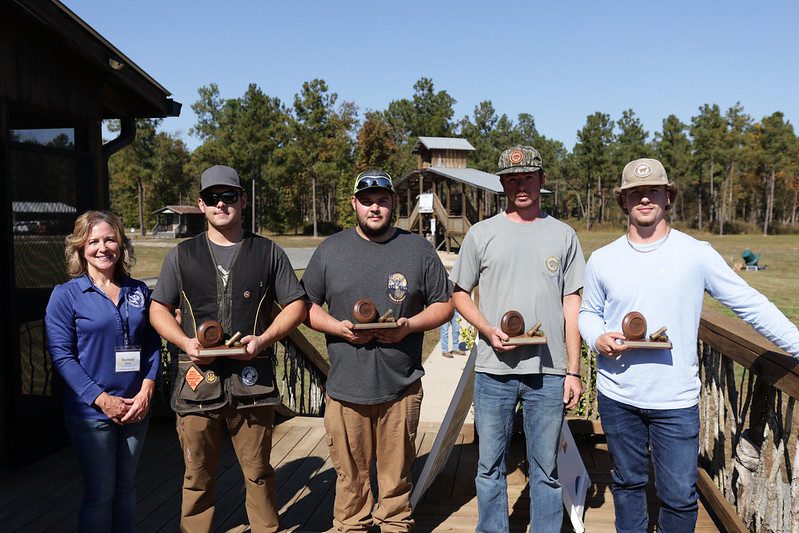 A woman and four men posing together at the South Piedmont Foundation's Clay Shoot Classic.