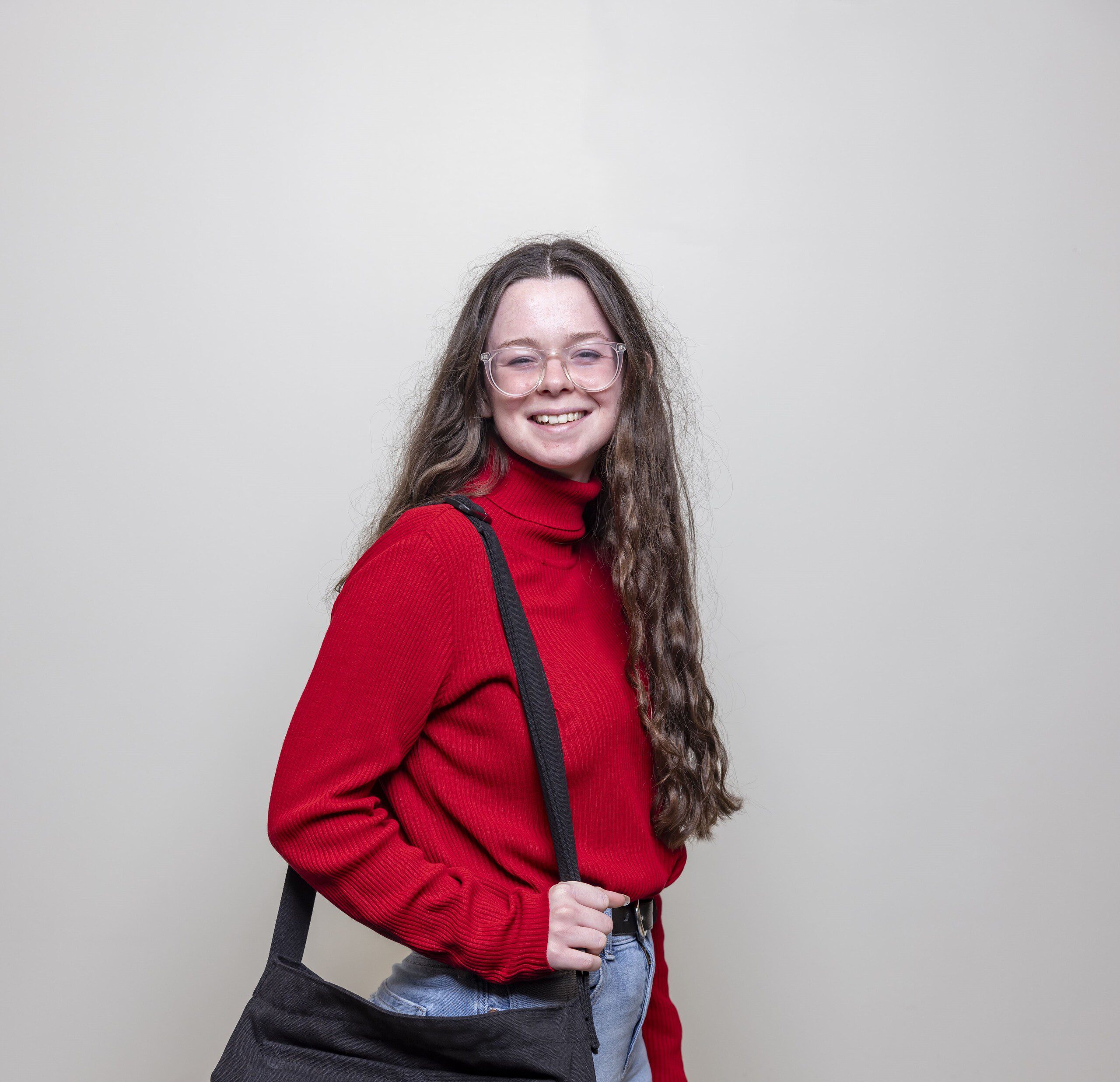 A full shot of a female student standing confidently in a hallway, looking at the camera.
