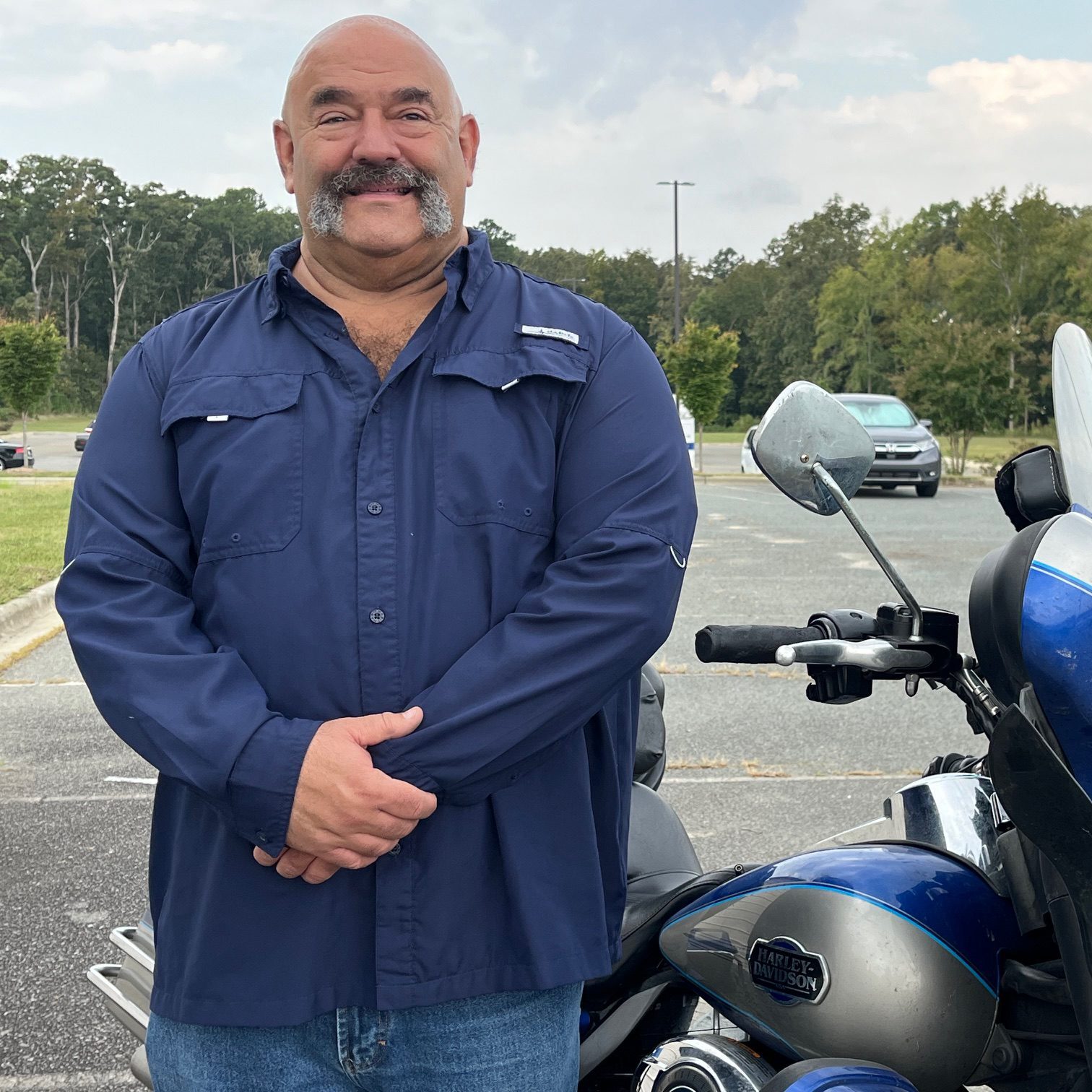 Jeff Gross posing with a blue Harley Davidson motor bike.