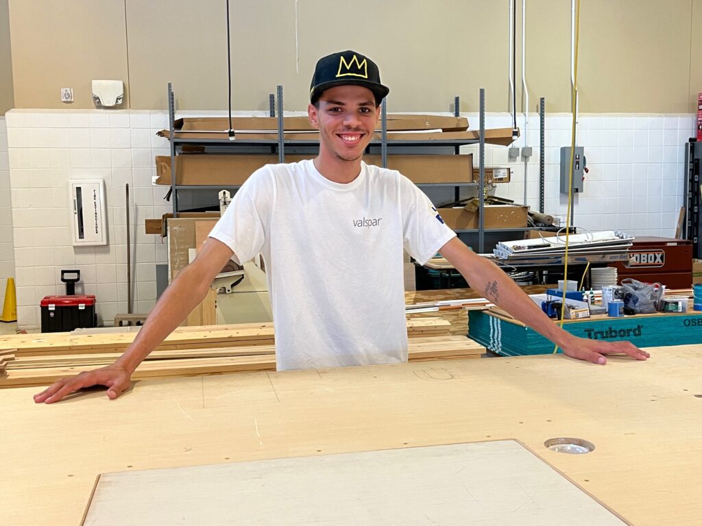 Justin McCoy inside a construction workshop, smiling at the camera.