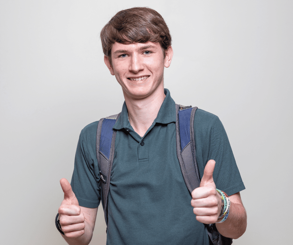 Photo of a white male student smiling at the camera and giving two thumbs up.