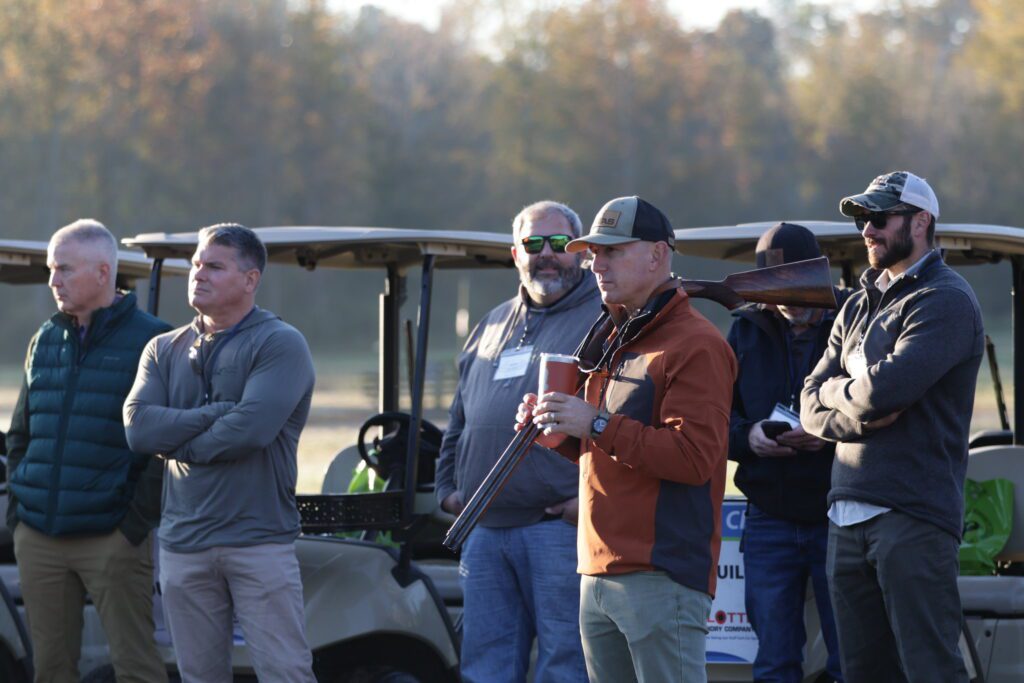 A group of men standing next to golf carts.