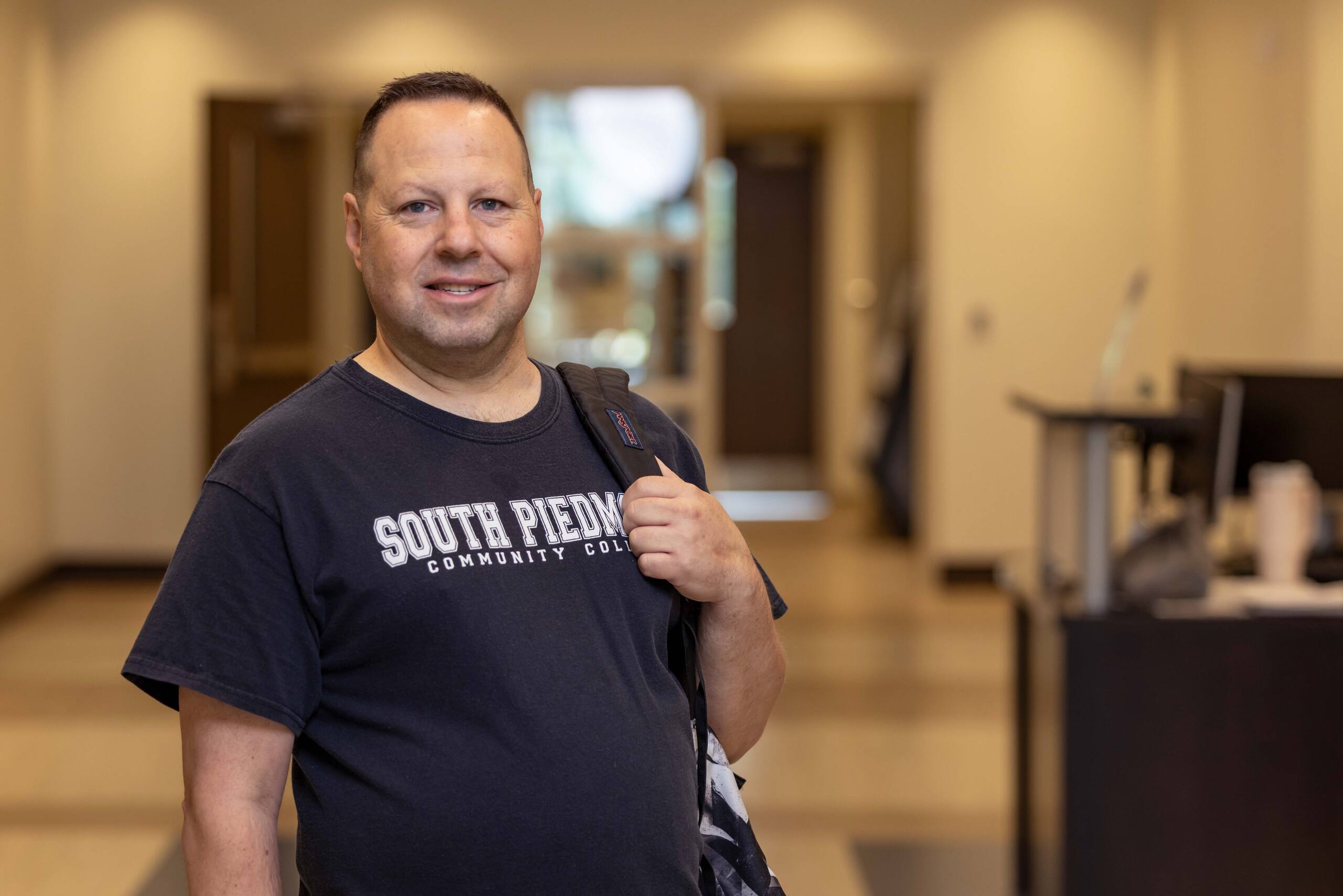 Adult South Piedmont student standing outside the cafeteria inside OCH main building.