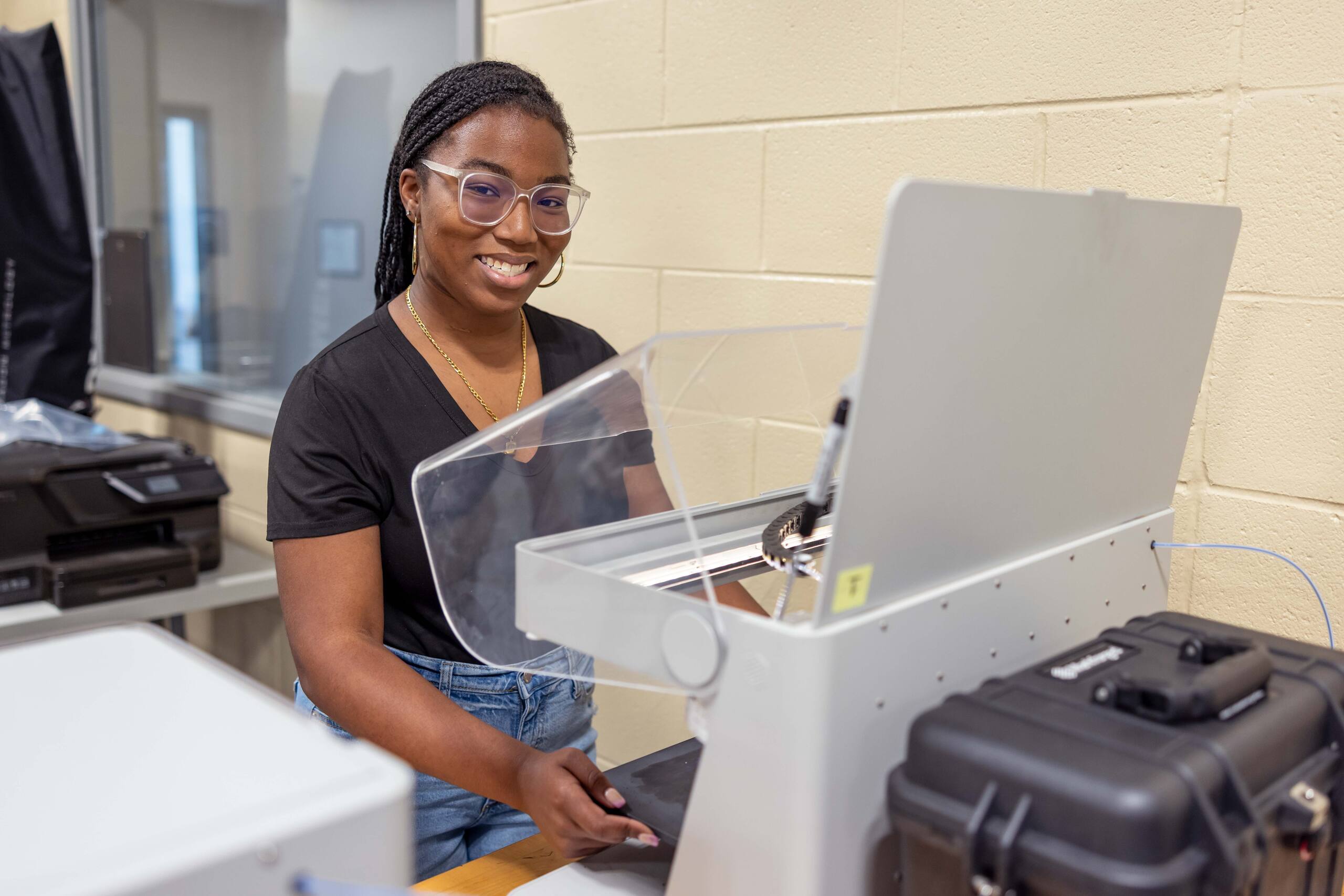 A student standing in front of a manufacturing machine in a training environment.