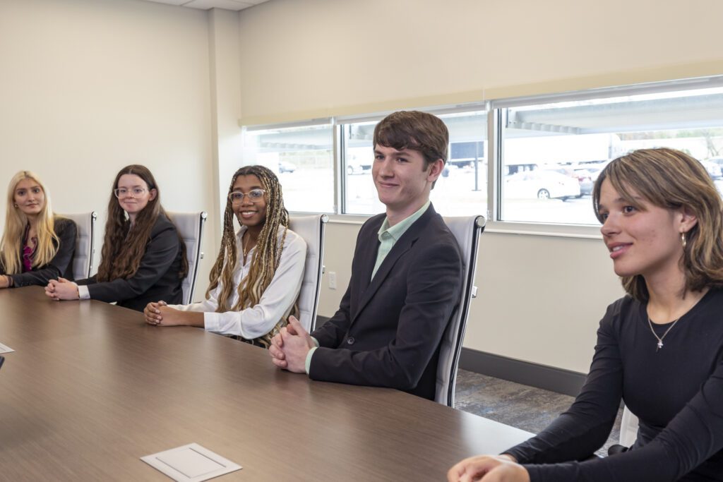 Students in business casual attire seated and attentively listening.