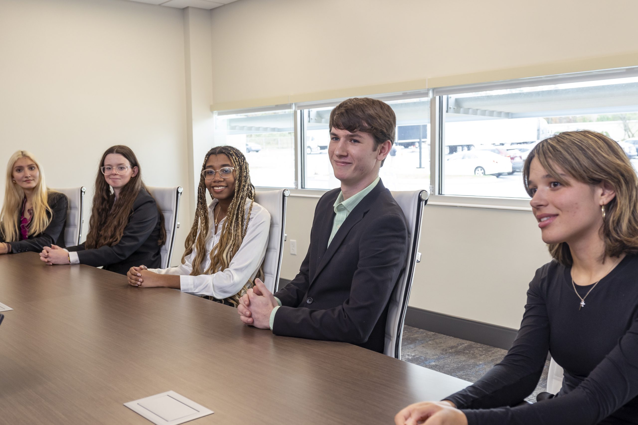 Students in business casual attire sitting and listening attentitvely.