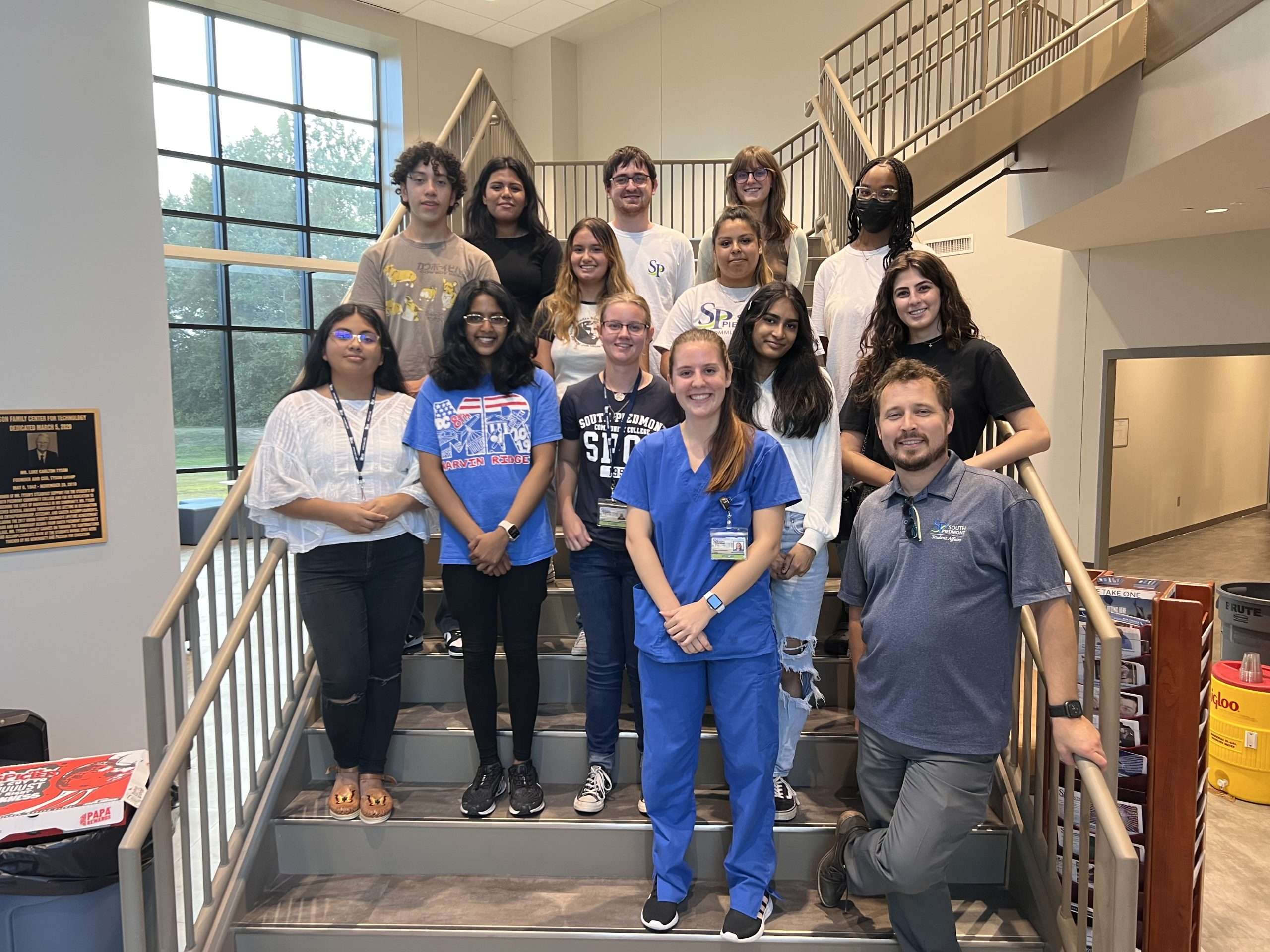 Group of students and their club supervisor posed on a staircase.