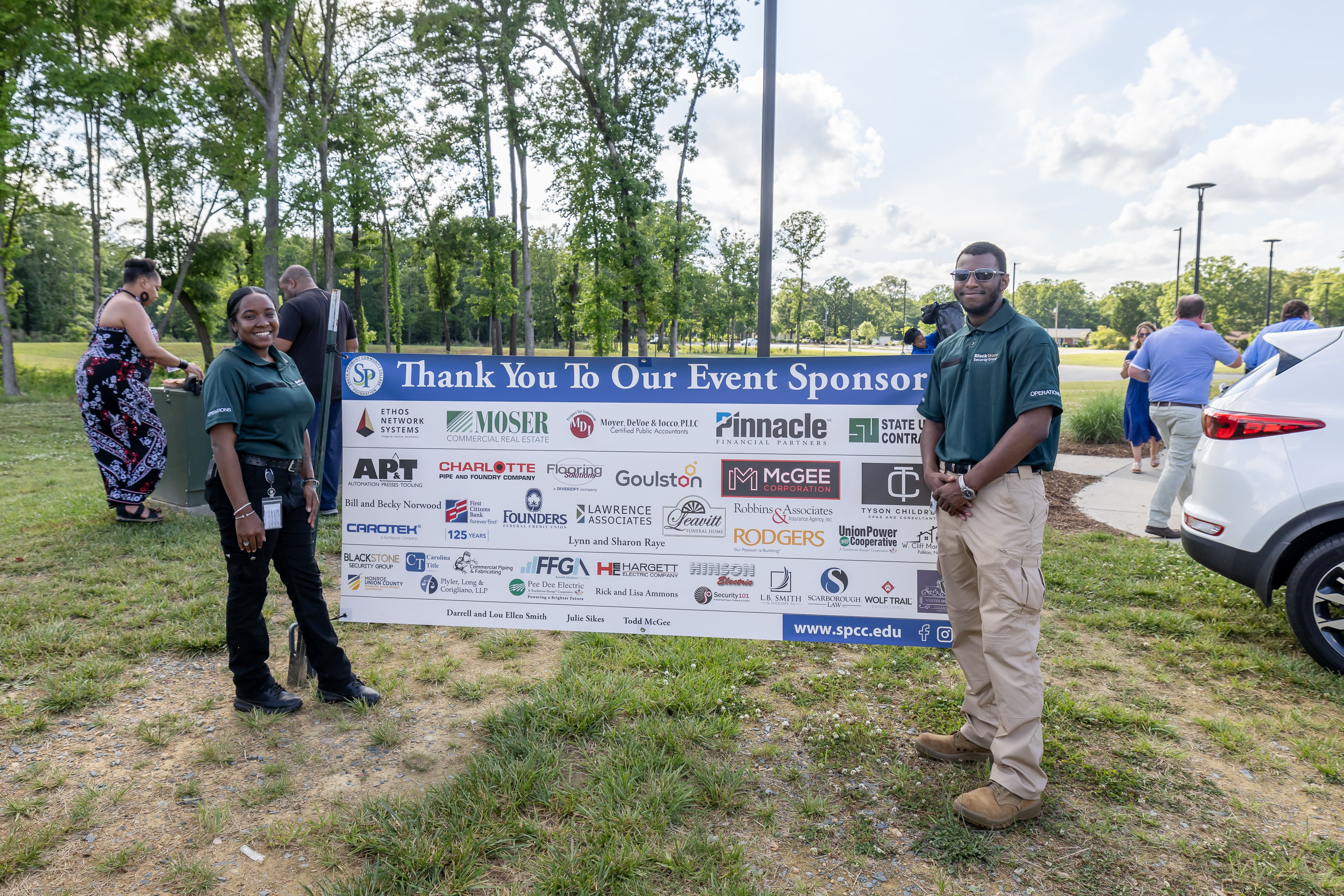 A man and a woman standing next to a "Thank You to Our Sponsors" sign.