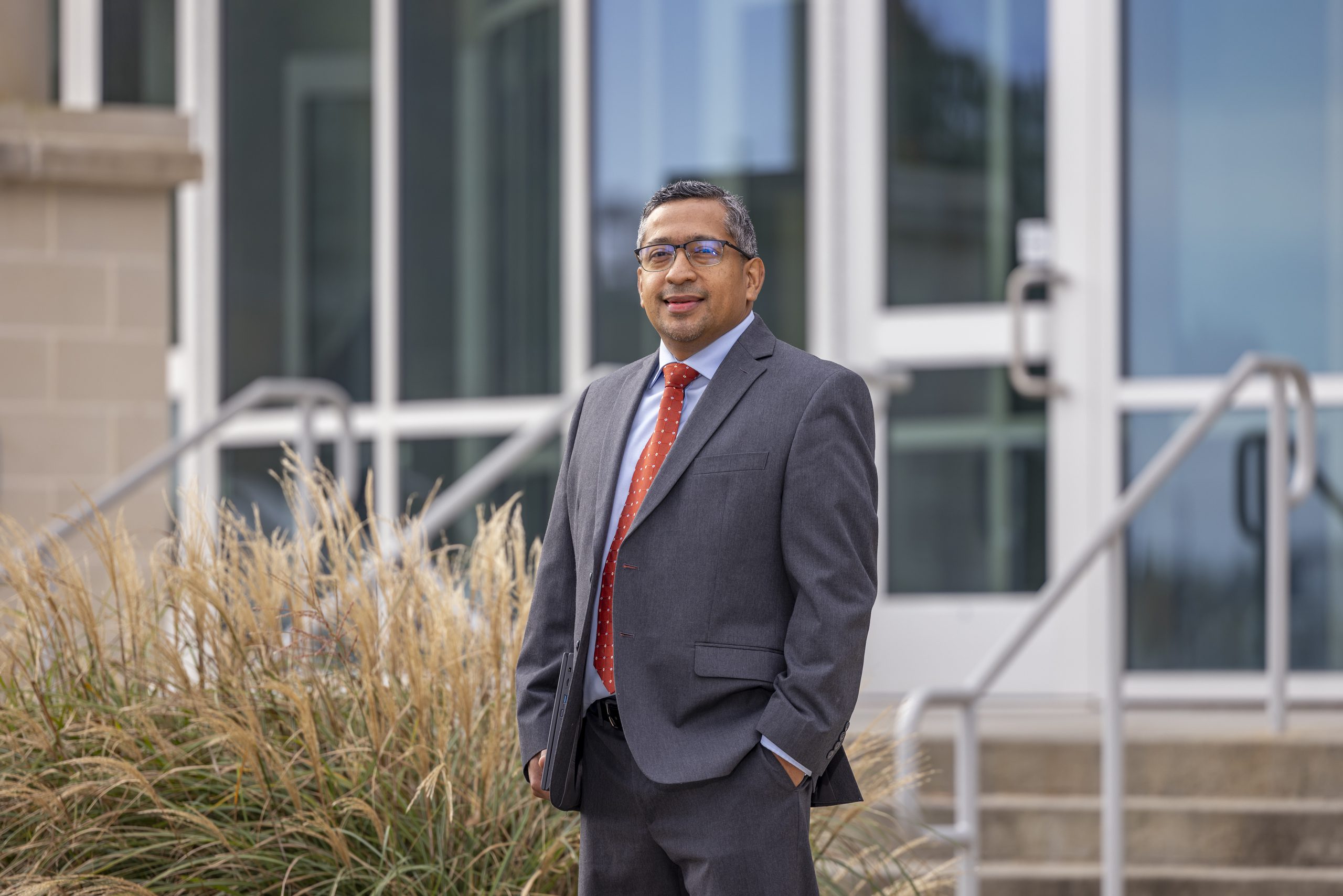 Student in business professional attire standing outside.