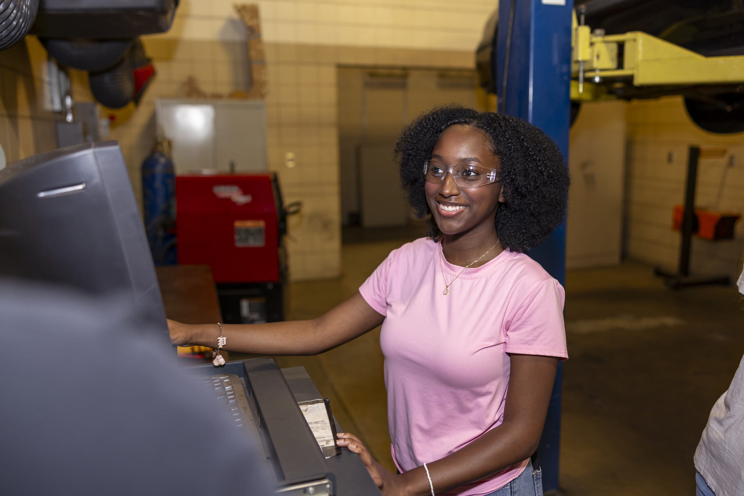Student in front of a computer inside an auto shop.