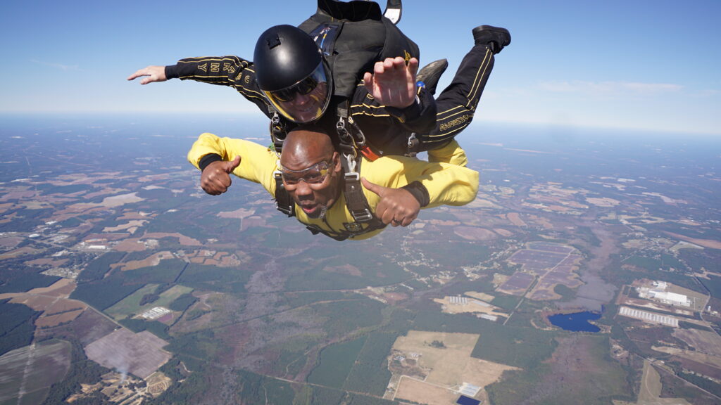 Dr. JJ Evans Skydiving Photo of a man in a yellow shirt skydiving.