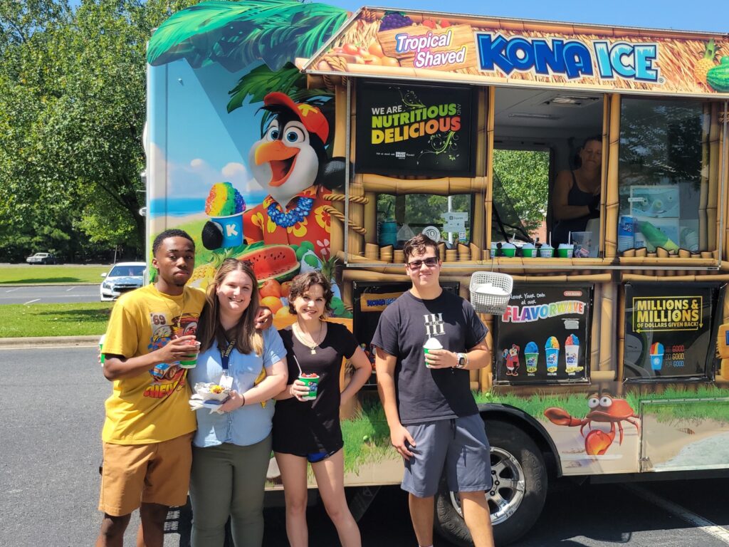 Photo of four students standing next to a Kona Ice truck.