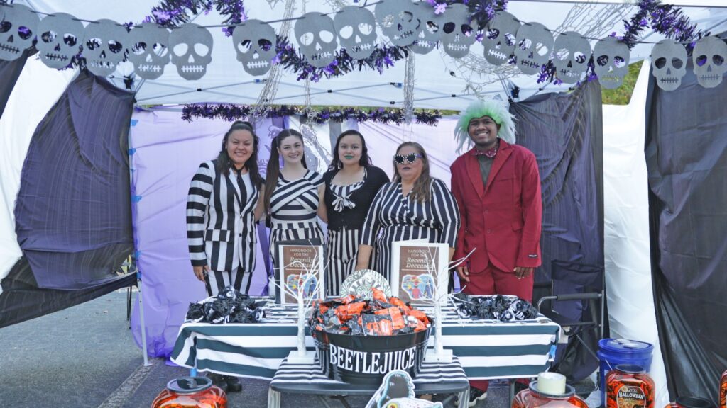Students and employees standing around a Beetlejuice-themed Halloween display.