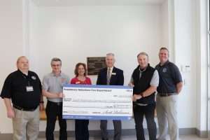 A group of people holding a large check in the lobby of South Piedmont's Braswell Building.