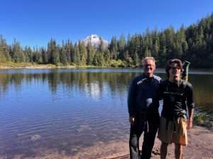 Photo of two men standing by a mountain lake.