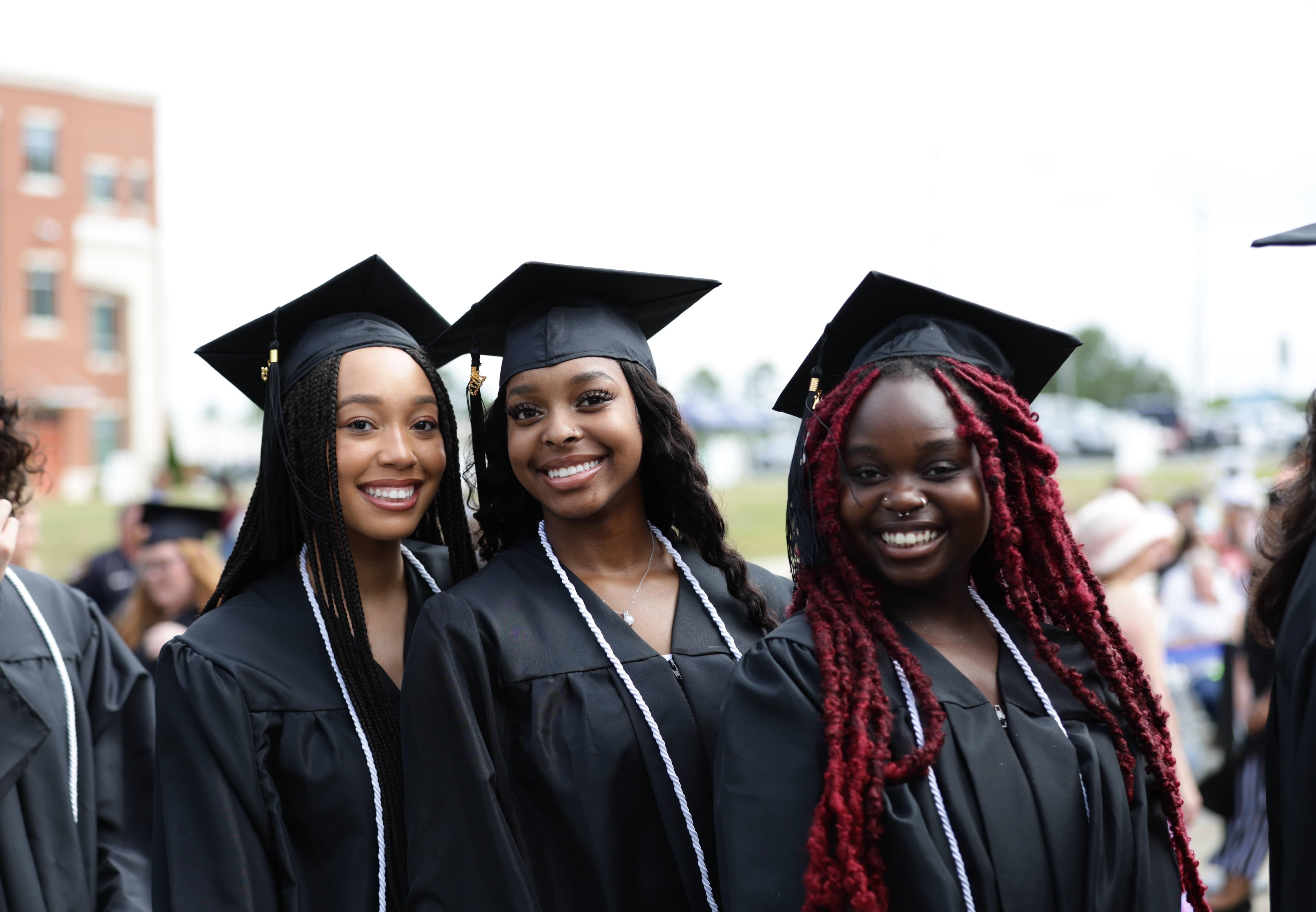 Three female students at graduation in their caps and gowns.