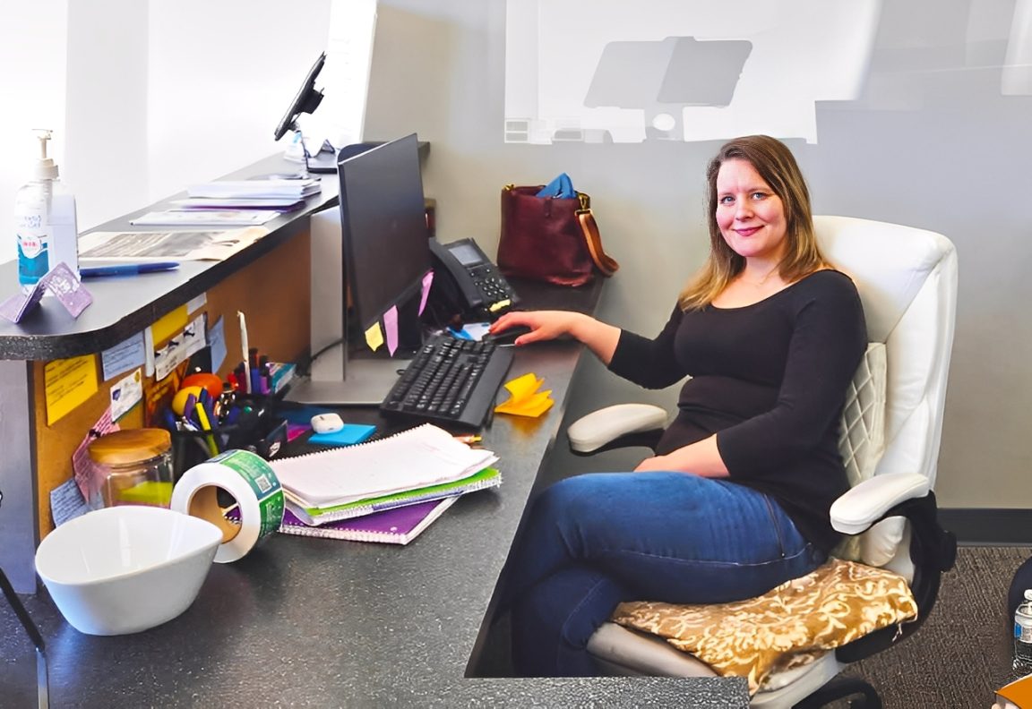 South Piedmont Healthcare administration student smiling at the camera while working at her desk.