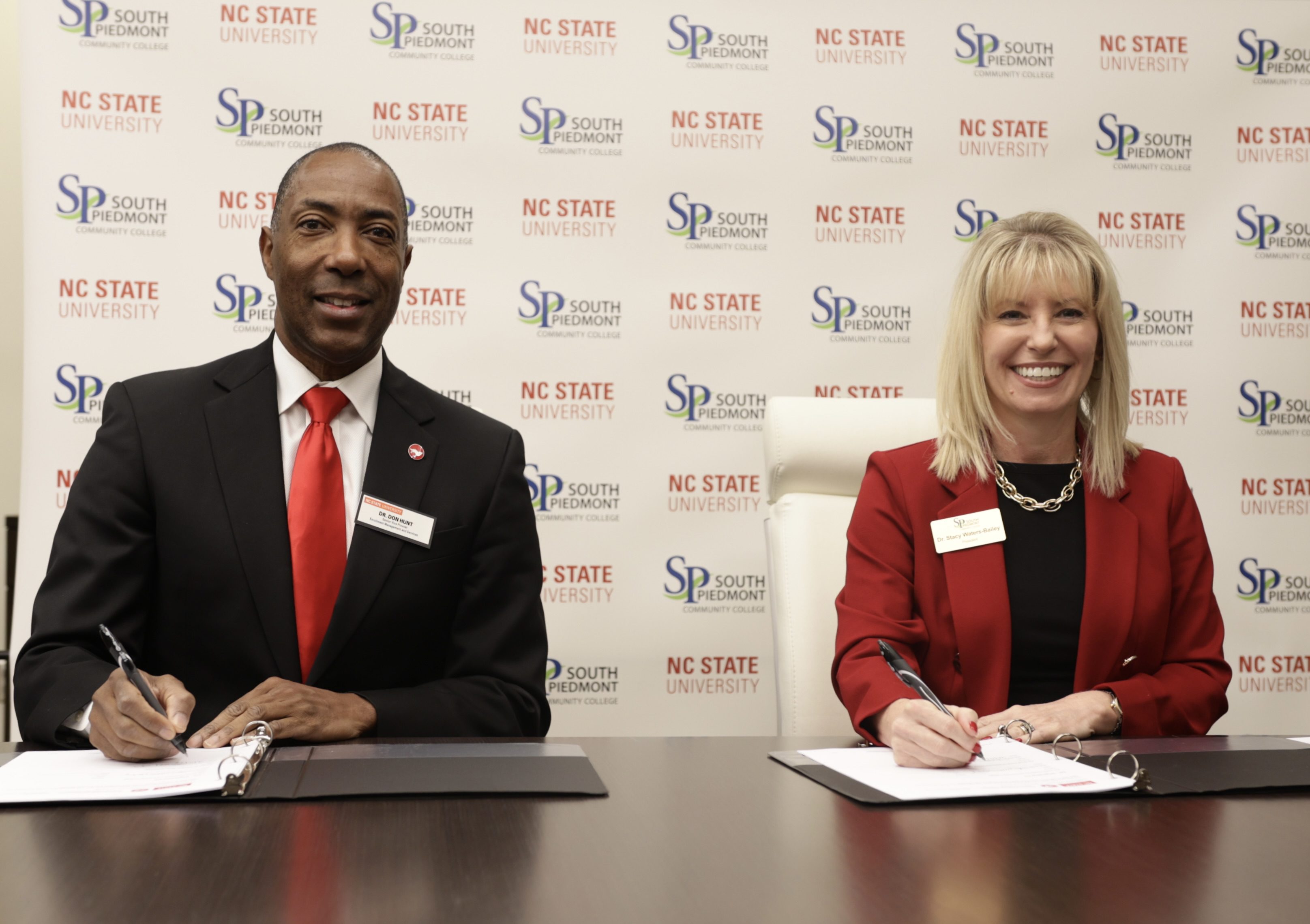 A man and a woman signing papers at a table.