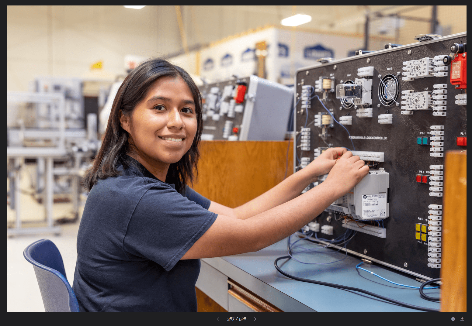 Student smiling in front of mechatronics equipment.