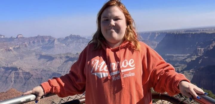 A woman in a red sweatshirt in front of the Grand Canyon.