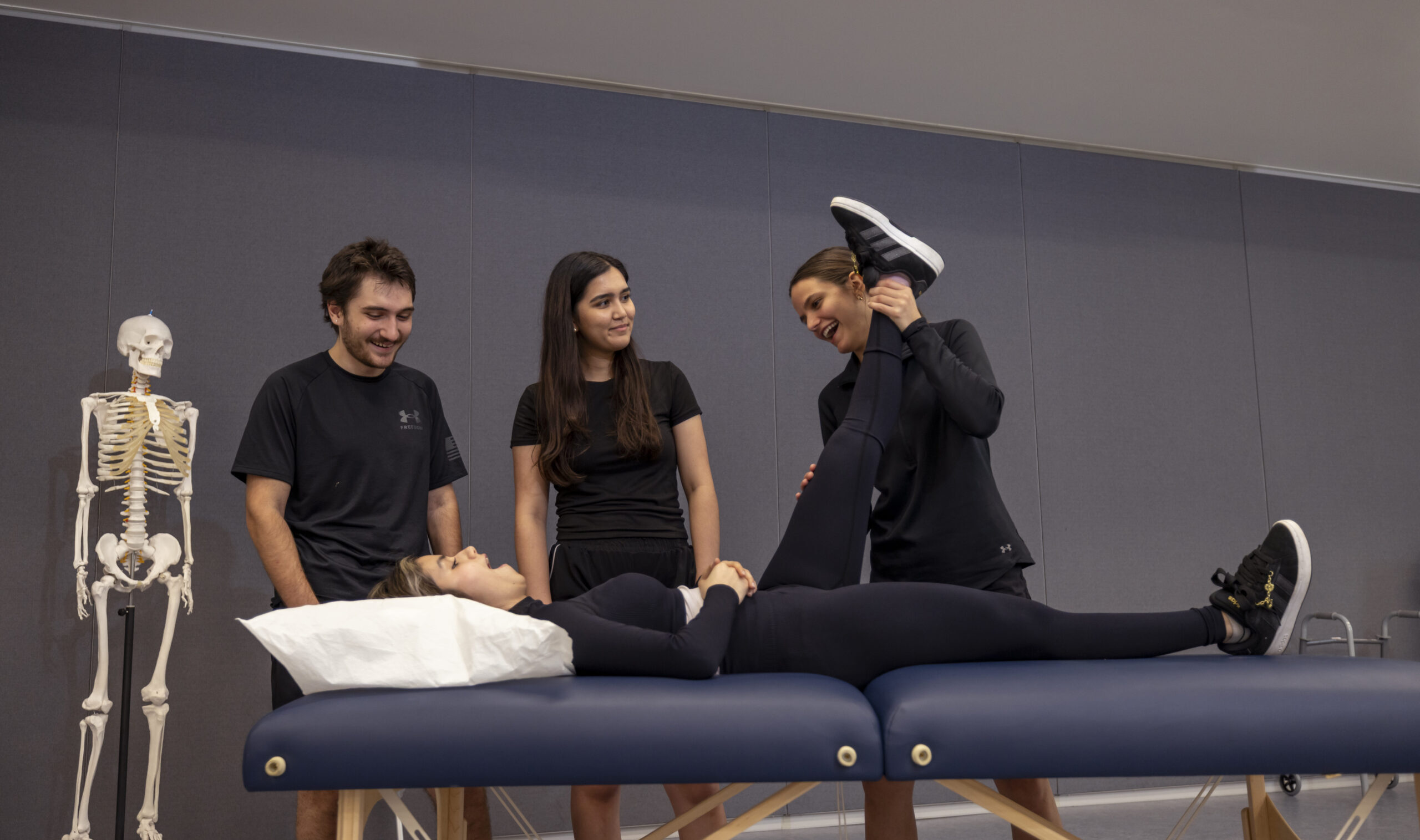 Physical Therapy students practice amongst themselves, one student helping with stretching.