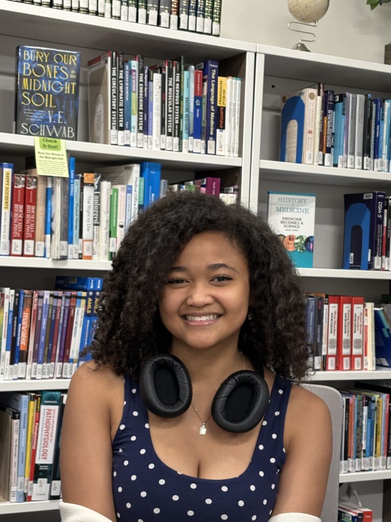 A girl with a great smile. She is wearing headphones and has curly hair.