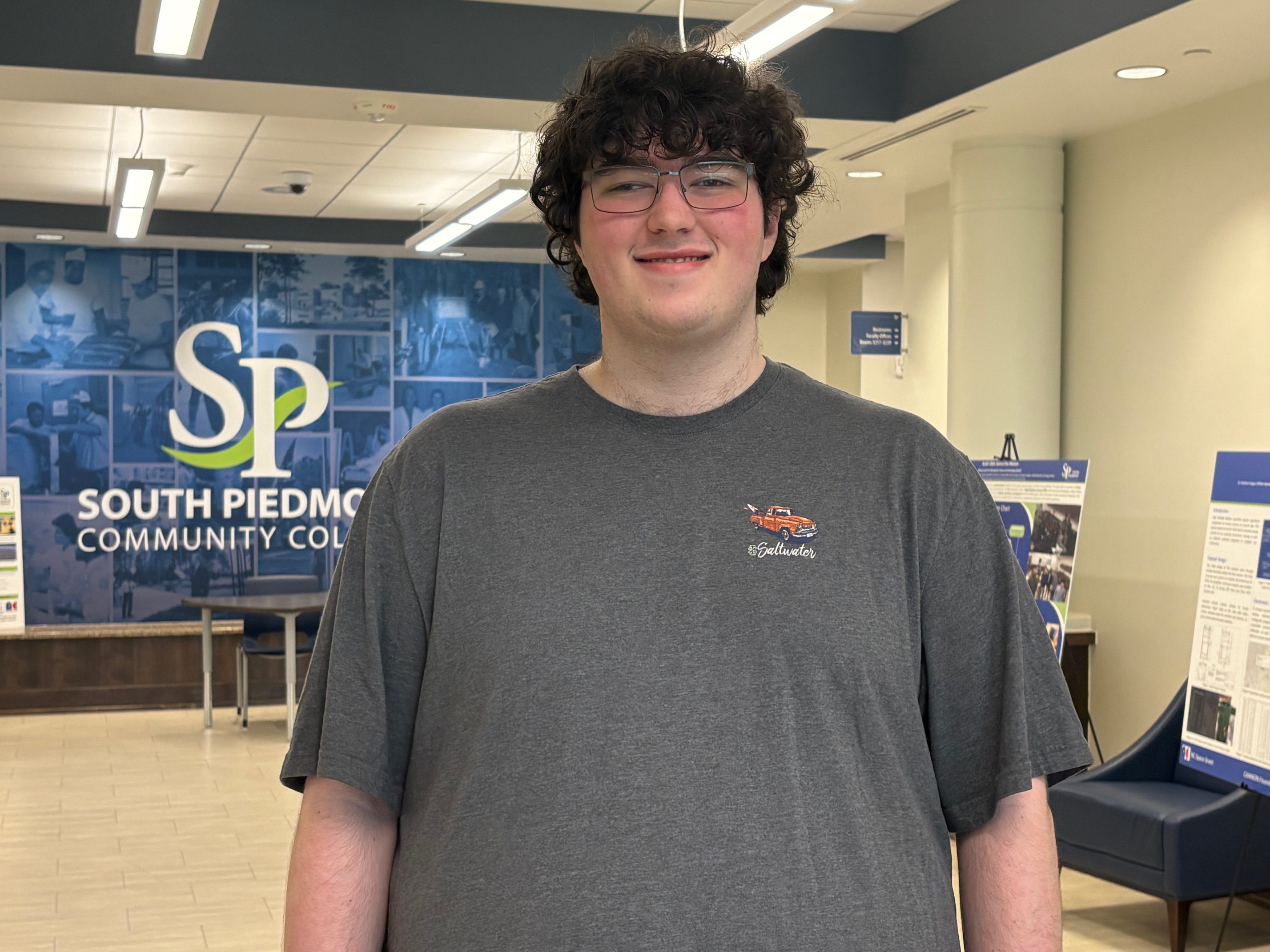 A man with curly hair, a grey shirt, and glasses.