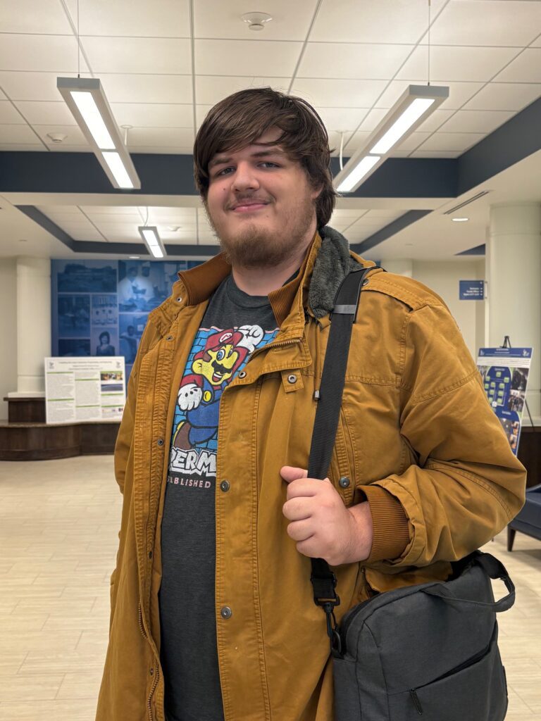 A man in a brown jacket with a bookbag.