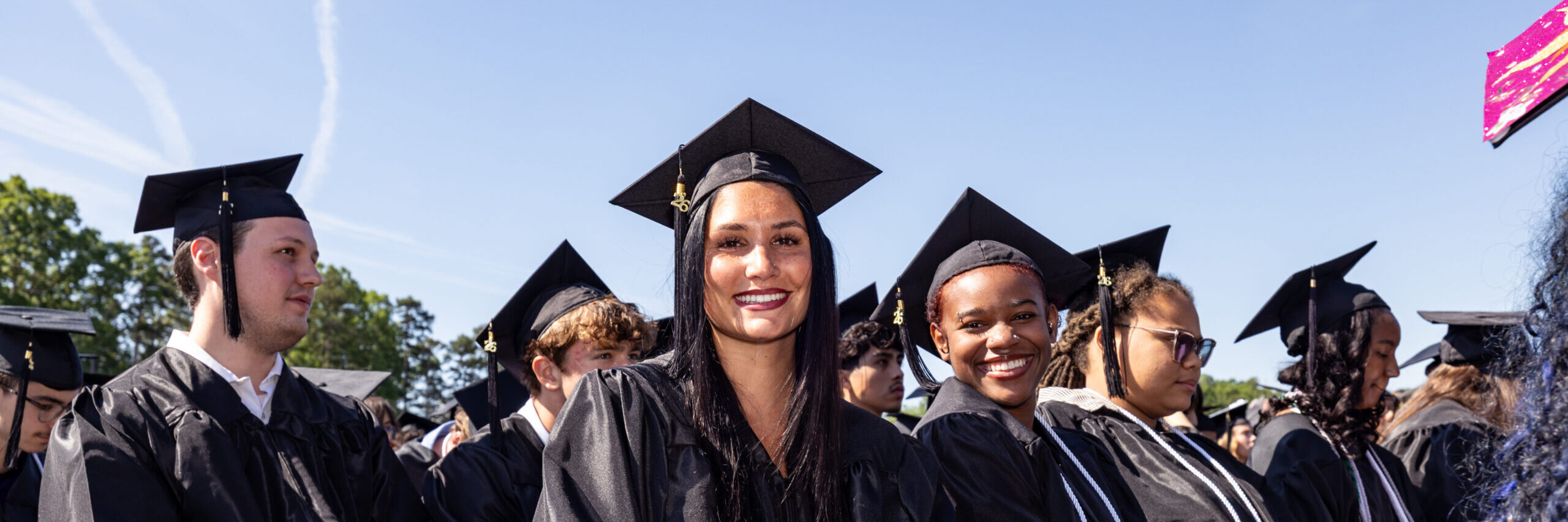 Group of recent graduates sitting and smiling at the camera.
